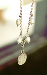 ORGADA's White Wisdom necklace hung and photographed on a blurry background