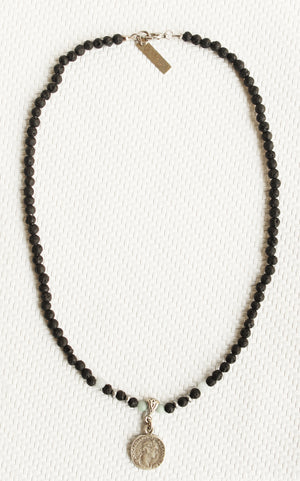 ORGADA necklace made of black lava beads and a replica coin photographed in full view
