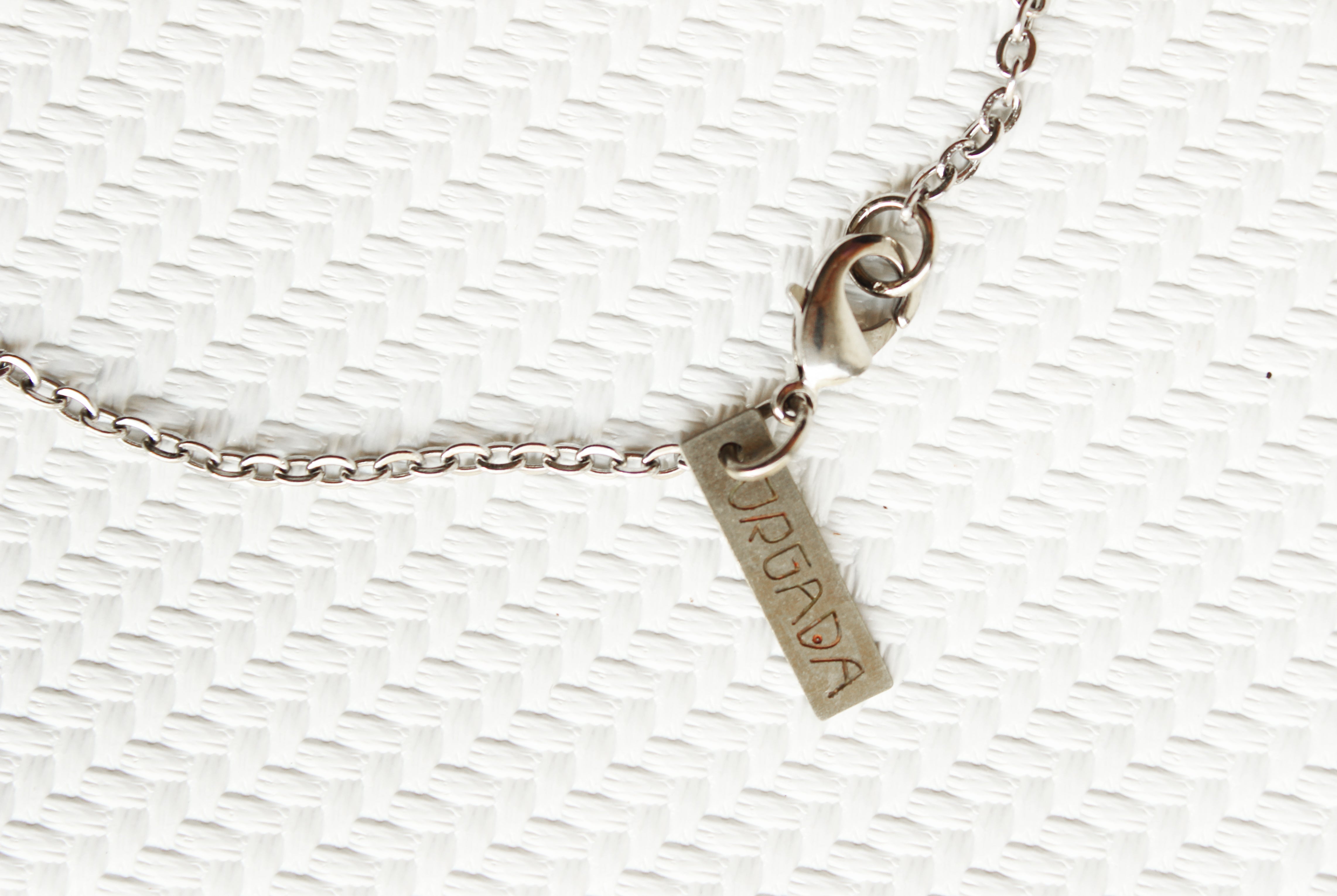 ORGADA's White Wisdom necklace hung and photographed on a white background in close-up of the lobster clasp closure