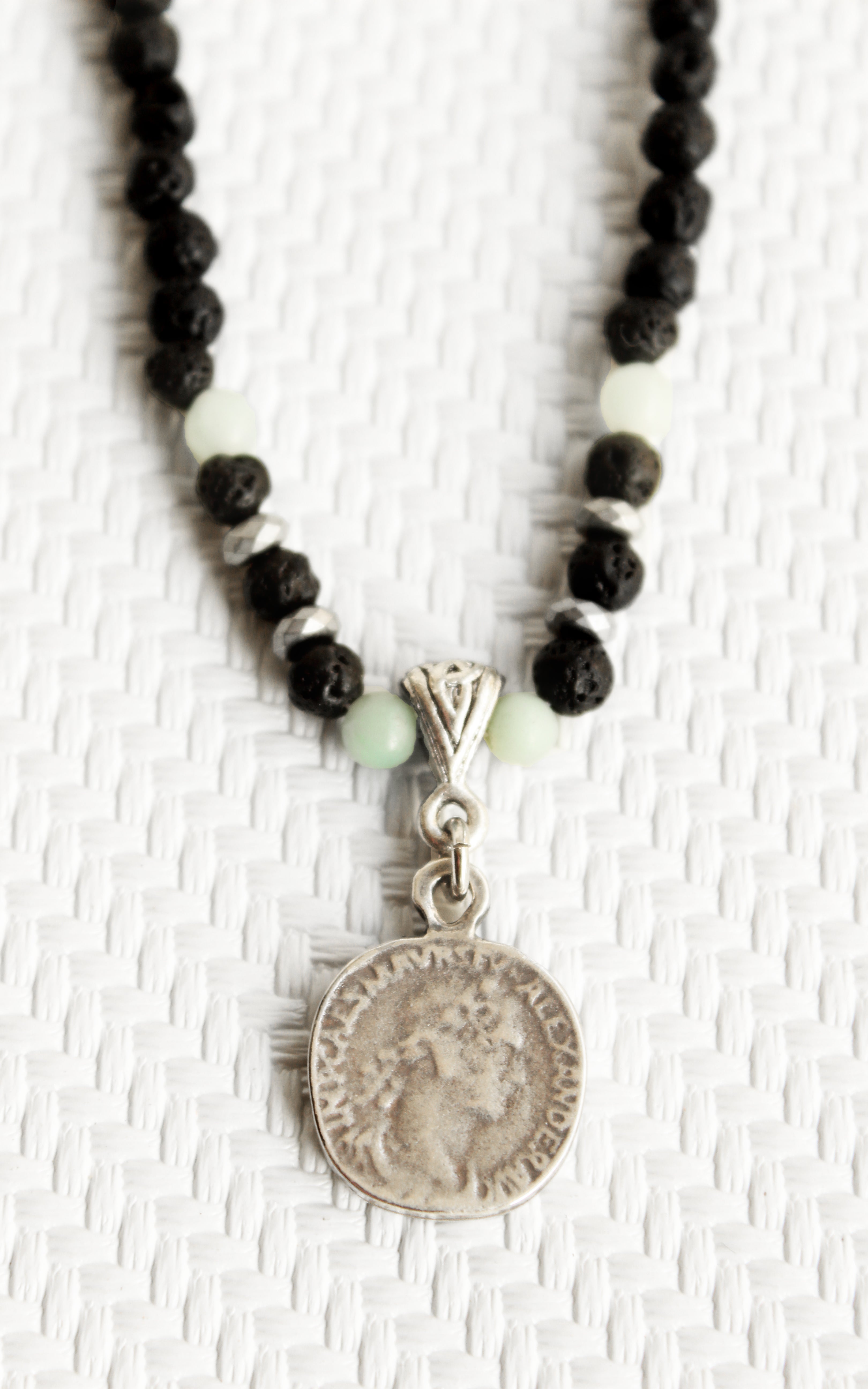 ORGADA necklace made of black lava beads and a replica coin photographed in close-up