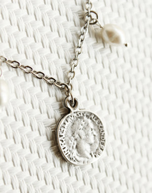 ORGADA's White Wisdom necklace hung and photographed on a white background in close-up of the replica coin pendant